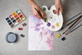 Woman painting flowers with watercolor at stone table, top view Royalty Free Stock Photo