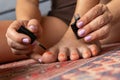 Woman painting her toenails with orange nail polish