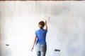 Woman painting new apartment walls in color white with paint roller. Renovating house