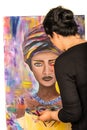 Woman painting portrait of african woman on canvas