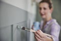 Woman Painting Wall With Panelling In Room Of House With Paint Brush