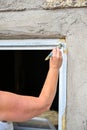 woman painting white on window frame on old barn