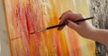 Woman paintress painting abstract picture using brush on canvas, hand closeup.