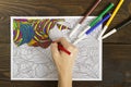 Woman paints coloring book for adults.