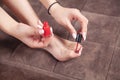 Woman paints her toenails with red pedicure
