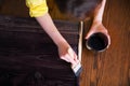 A woman paints planks with a stain of ebony wood stain.