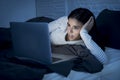 Woman in pajamas on bed at home bedroom working concentrated with laptop computer late at night