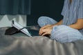 Woman in pajamas sitting on bed in bedroom working with laptop.