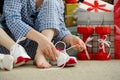 Woman in pajamas ties the laces of athletic shoes.