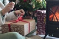 Woman in pajamas unwrapping gift box on Christmas morning