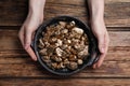 Woman with pan of gold nuggets at wooden table, top view Royalty Free Stock Photo