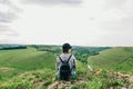 Woman in panama and casual clothes sits on a rock and looks at a beautiful landscape with a river and fields. Girl hiker resting Royalty Free Stock Photo
