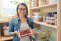 Woman in pantry holding container with red bitter chili pepper