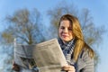 The woman in park on a background of the blue sky and reads the newspaper. female reading newspaper with happy, good