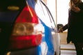 Woman in parking lot on blue car background. Opens door with key..