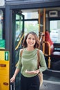 Woman passenger with backbag getting off the bus in vacation Royalty Free Stock Photo