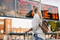 Woman passenger is checking arrival and departure board schedule timetable at train or bus station Royalty Free Stock Photo