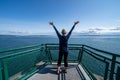 Woman passenger on the Port Townsend Ferry in Washington State stands with her arms up and back to the camera as the boat sails Royalty Free Stock Photo