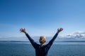 Woman passenger on the Port Townsend Ferry in Washington State stands with her arms up and back to the camera as the boat sails Royalty Free Stock Photo