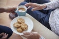 Woman passes tea and biscuits to a seated senior man, detail Royalty Free Stock Photo