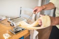 Woman passing a pasta sheet through a machine