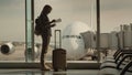 A woman with a passport and a boarding pass is standing at the huge window, behind which you can see the airliner. Start