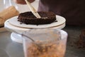 Woman pastry chef impregnates chocolate sponge cake on stand, close-up. Cake making process, Selective focus Royalty Free Stock Photo
