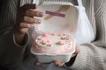 Woman pastry shef wearing white apron and holding small bento cake decorated with cream cheese pink flowers. Woman hands hold Royalty Free Stock Photo