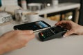 A woman paying for coffee with a smartphone by PAY PASS