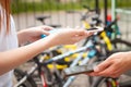 woman pays for a bike rental using a phone and a bank card. mobile payment. Rent a bike for the day. Technology