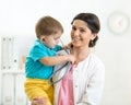 Woman pediatrician holding in her arms kid boy patient in office Royalty Free Stock Photo