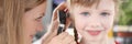 Woman pediatrician looking at eardrum of little girl using otoscope in clinic