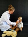 Woman pediatrician in mask measures the temperature of a little boy Royalty Free Stock Photo