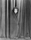 Woman peek-a-booing behind a curtain