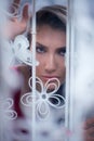 Woman peek out from behind white curtain near the window