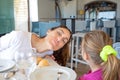 Woman looking out to say hello next to daughter in restaurant Royalty Free Stock Photo