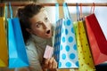 Woman peeking out from shopping bags with red credit card