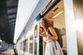 Woman peeking out train. Woman railway station. Young happy woman pulling face out train door looking for somebody Royalty Free Stock Photo