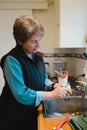 A woman peeling potato on a kitchen with wooden bench