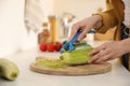 Woman peeling zucchini at kitchen counter, closeup. Preparing vegetable Royalty Free Stock Photo