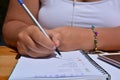 Woman, pen in hand, writing in a bullet journal