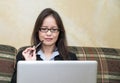 Woman with pen and laptop on sofa Royalty Free Stock Photo