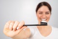 A woman with a perfect smile holds a toothbrush with toothpaste in the foreground. Oral hygiene