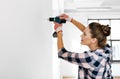 woman with perforator drilling wall at home