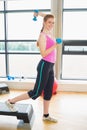 Woman performing step aerobics exercise with dumbbells Royalty Free Stock Photo