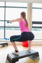 Woman performing step aerobics exercise with dumbbells Royalty Free Stock Photo