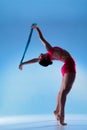 Woman performs assisted standing backbend stretch with strap in blue studio Royalty Free Stock Photo