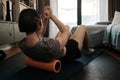 A woman performs a crunch while positioned on a foam roller, engaging her core and upper back during a focused home workout. Royalty Free Stock Photo