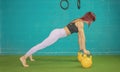 Woman performs a solid front plank while holding two yellow kettlebells, keeping her legs fully extended and her body straight and Royalty Free Stock Photo