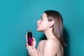 Woman with perfume bottle in studio. Girl with perfume, young beautiful woman holding bottle of perfume and smelling Royalty Free Stock Photo